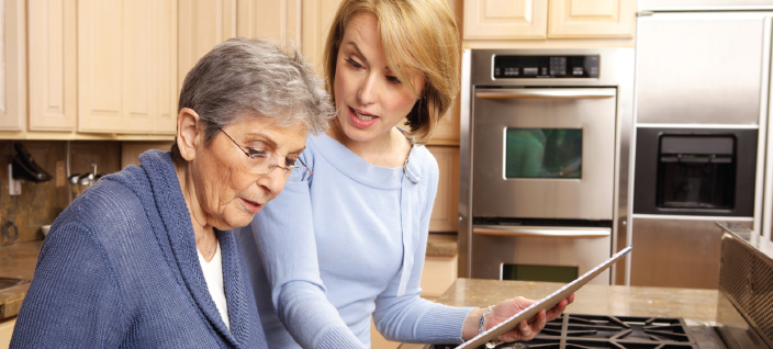 Older woman getting help with medication from female companion.