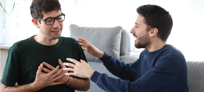 Two men having conversation on couch. 