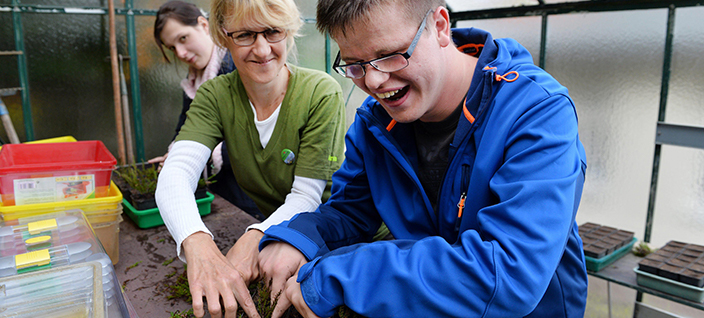 Young man smiling and helping woman plant seeds