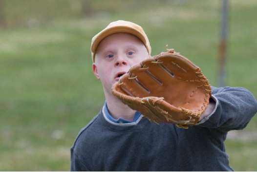 Young man with down syndrome ready to catch baseball with glove. 