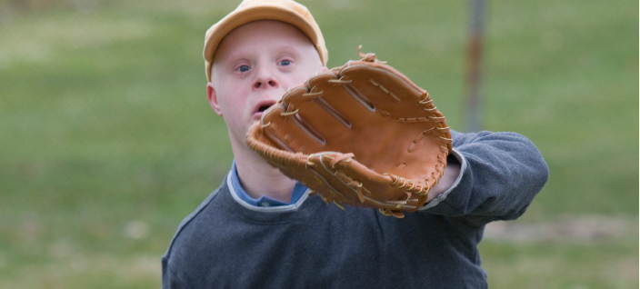 Young Man Catching Baseball Young man with down syndrome ready to catch baseball with glove.