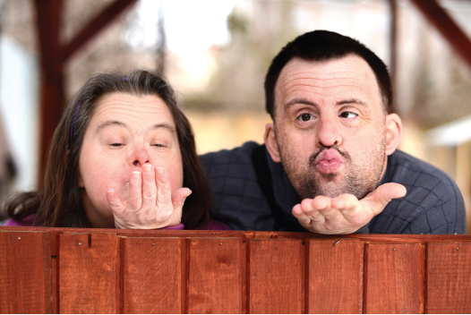 Man and woman with down syndrome blowing kissing to camera