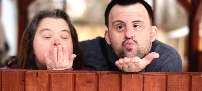 Man and woman with down syndrome blowing kissing to camera