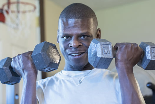 Man curling dumbells and looking at camera