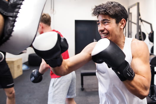 Young man smiling while learning kickboxing